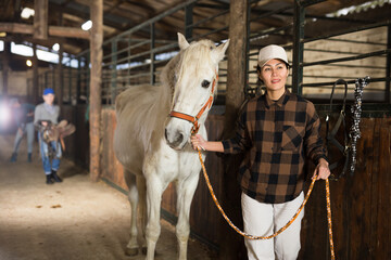Portrait of asian woman with white horse in stable closeup