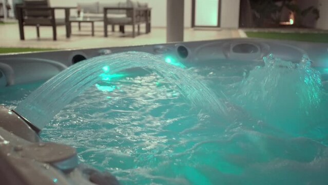 Close-up of the surface of a modern hot tub for relaxation therapy and rehabilitation in a hotel. Bubbles of water in a bath under oxygen pressure In evening outside with lights
