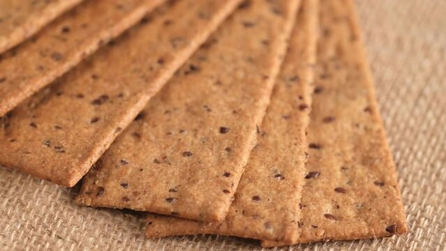 Ruddy bread rolls on the fiber.Beautifully laid out loaves. Crunchy crisp breads with sesame and flax seeds. Healthy dietary meal. macro. rotation. Baked bread slices. Whole grains