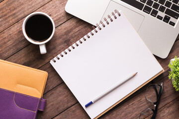 Office table with blank notebook and laptop / Coffee cup