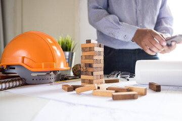 Construction engineers concept / close-up block of wood tower on the bench of the architect and the analysis of the project architecture.