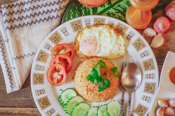 Fried Rice with Fried Egg Put on the wooden table and the tomatoes, cucumbers, garlic, shallots