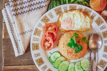 Fried Rice with Fried Egg Put on the wooden table and the tomatoes, cucumbers, garlic, shallots