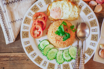 Fried Rice with Fried Egg Put on the wooden table and the tomatoes, cucumbers, garlic, shallots