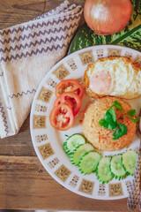 Fried Rice with Fried Egg Put on the wooden table and the tomatoes, cucumbers, garlic, shallots