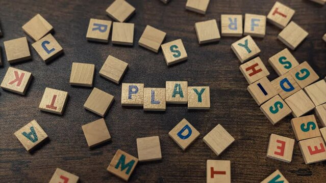 Zoom in the word PLAY made of scattered wooden alphabet letters on the brown wooden table . High quality 4k footage