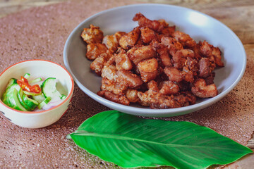 Fried Pork Belly with Fish Sauce and Sticky Rice Served on a white plate on a black wooden floor.