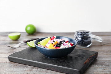 Board with bowl of tasty Mexican vegetable salad on wooden table