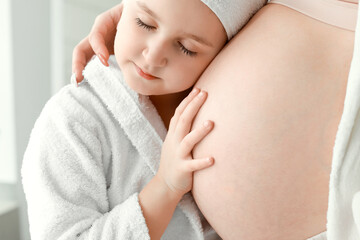 Little girl with her pregnant mother at home in morning