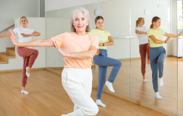Obraz premium Aged lady dancing with her family in studio during group aerobic training.