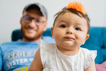 portrait baby latina girl with doubtful face, in the legs of her father, close up