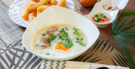 Chinese style porridge or porridge and fried dough stick or fried dough stick or donut or fried bread placed on a wooden table. Thai street food is called 