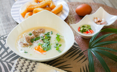 Chinese style porridge or porridge and fried dough stick or fried dough stick or donut or fried bread placed on a wooden table. Thai street food is called 