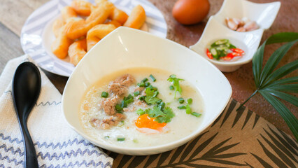 Chinese style porridge or porridge and fried dough stick or fried dough stick or donut or fried bread placed on a wooden table. Thai street food is called "porridge" and "Patongo".