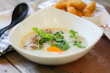 Chinese style porridge or porridge and fried dough stick or fried dough stick or donut or fried bread placed on a wooden table. Thai street food is called 