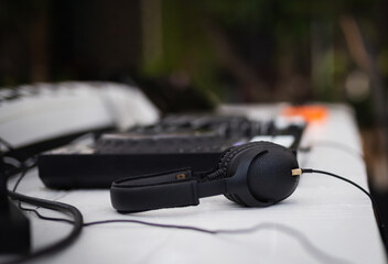 Black headphones and professional mixing console on table.