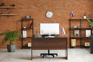 Interior of modern office with computer and Russian flag on dark wooden table