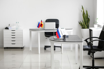 Russian flag, stationery holder, laptop and landline phone on table in office