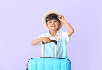 Little boy with suitcase on color background