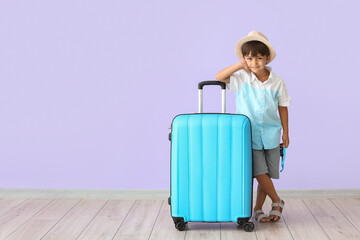 Little boy with suitcase on color background