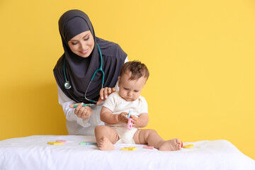 Muslim pediatrician vaccinating baby boy on color background