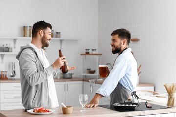 Young brothers drinking beer in kitchen