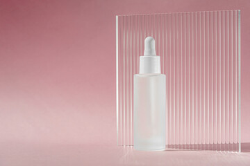 Serum oil with collagen and peptide in white transparent bottle with dropper on pink decor backdrop...