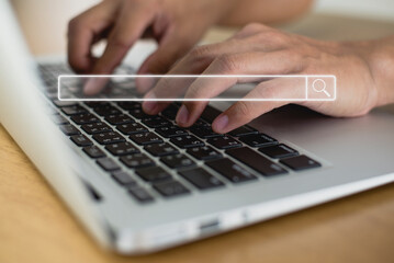 Close up image hand of young businessman use their tying keyboard on laptop to find out what interests them, to find ideas about networking and online learning with search bar icon.