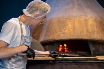 Italian chief-cooker baking pizza in the restaurant