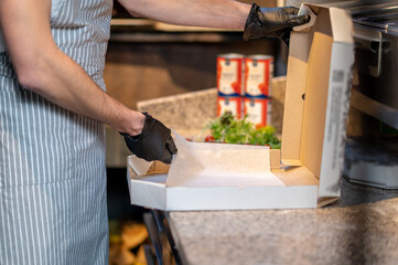 A baker packing pizza in the kitchen
