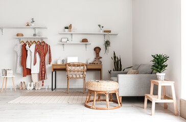 Interior of stylish room with workplace and rack with clothes