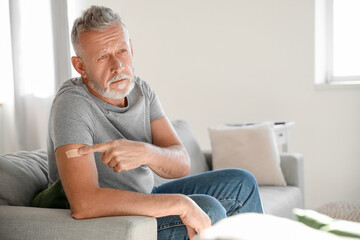 Mature man with applied nicotine patch at home. Smoking cessation - obrazy, fototapety, plakaty