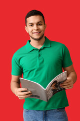 Young man reading magazine on red background