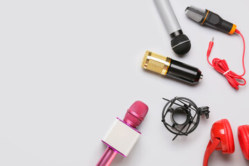 Modern microphones with headphones on light background