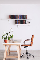 Table and books on shelves hanging on wall in interior of room