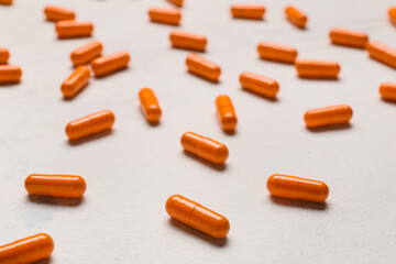 Turmeric powder capsules on light background, closeup