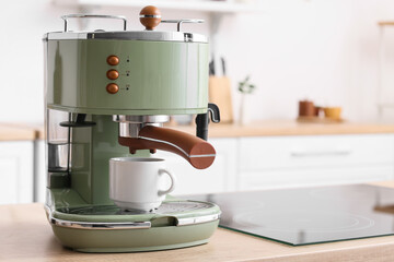 Modern coffee machine with cup on counter in kitchen