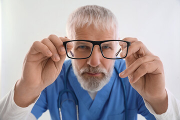 Mature male doctor with eyeglasses on white background