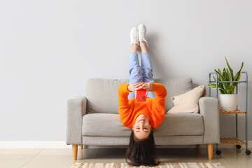 Beautiful young woman with mobile phone resting on couch at home