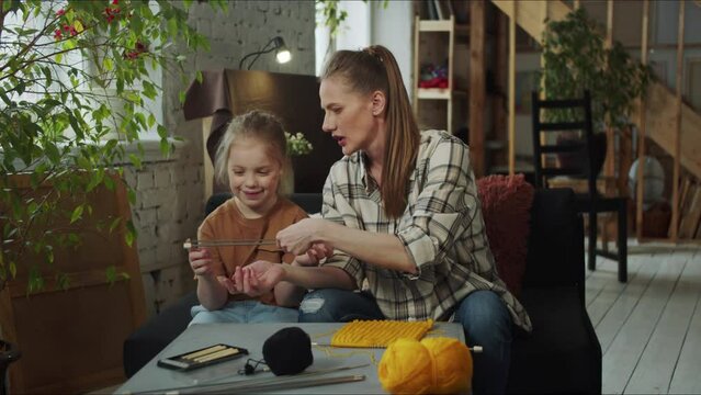 Woman showing a girl a knitting needle