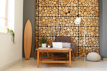 Interior of modern living room with wooden surfboard, tables and armchair