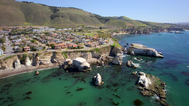 Picturesque town along California coast overlooking the vivid blue Pacific Ocean from up on cliffs (Aerial 4K drone footage)