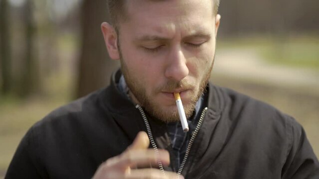 Male person smoking a cigarette. This is his unhealthy daily habit. Footage for topics like cigarette smoke, nicotine addiction, health danger, lung cancer, bad smell, slow death, physical illness.