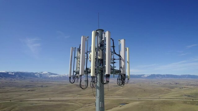 Aerial video of a cell phone tower in a rural area with mountains in the background