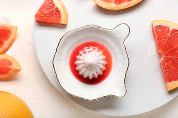 Ceramic juicer and grapefruits on light background
