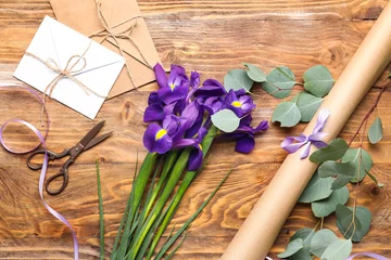 Tuinposter Composition with beautiful iris flowers, scissors, envelopes and wrapping paper on wooden background © Pixel-Shot