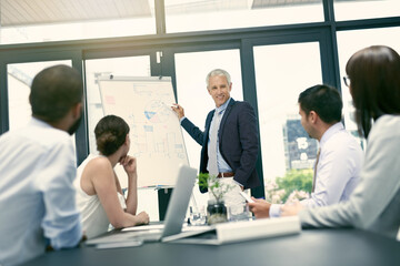 Explaining the companys financials. Shot of a group of businesspeople in a presentation.