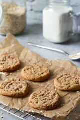 baked oatmeal cookies on baking rack with milk and oats, grey marble table