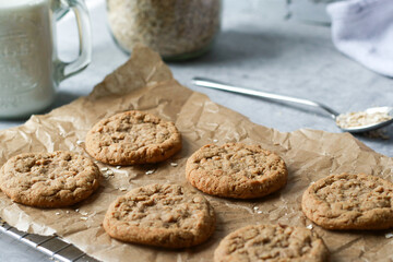 Obraz na płótnie Canvas fresh baked oatmeal cookies on baking rack, milk and oats in background 