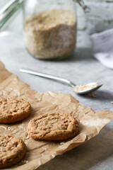 close up of fresh baked oatmeal cookies on baking rack, oats in background, grey marble table